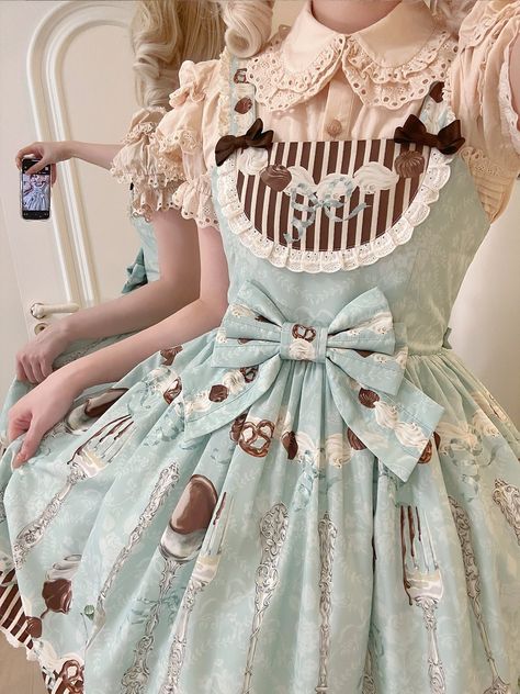 The dress boasts a comfortable and flexible design with a shirred back to ensure a perfect fit for various body types. The mint green hue provides a refreshing contrast to the rich chocolate dessert motifs, making it an eye-catching addition to any lolita wardrobe.  Pair it with a petticoat for extra volume, lace stockings, and a matching headpiece to complete your look. Dive into a world of sugary fantasies with our Mint Green and Chocolate Dessert Print Sweet Lolita Dress. SizeSMLXLBust76-8482-9088-9694-102Full Length89909192 Dessert Inspired Outfit, Refreshing Outfits, Dessert Clothes, Kawaii Dress Pastel, Dessert Dress, Fitted Fairy Kei Style Dress, Dessert Outfit, Fairy Kei Dress With Ruffles And Fitted Style, Whimsical Princess