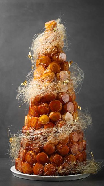 Kirsten Tibballs on Instagram: "Introducing my Croquembouche, a tower of sheer delight – available now on @savourschool online classes. Irresistibly puffed choux pastry filled with two luscious creme pâtissier flavors: zesty orange liqueur and decadent dark chocolate. Each choux is then dipped into toffee, for that extra layer of indulgence, and then assembled into a wonderous tower, finished with a golden swirl of spun sugar. Want to learn how to make my croquembouche? Head over to the li Choux Pastry Wedding Cake, Choux Pastry Tower, Croquembouche Aesthetic, Croquembouche Decoration, Choux Pastry Cake, French Wedding Cake Croquembouche, Croquenbuche Christmas, Croquembouche Wedding Cake, Croquembouche Christmas