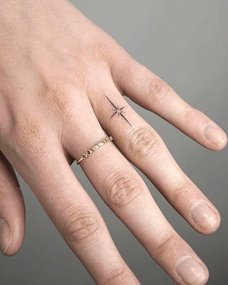 50 Dreamy Star Tattoos and Their Meanings (2022) - The Trend Spotter North Star Tattoo Finger, Star Ring Tattoo, Cross With Stars Tattoo, Star On Finger Tattoo, North Star Finger Tattoo, Delicate Star Tattoo, North Star Tattoo Meaning, Sparkle Finger Tattoo, 2022 Tattoo Trends