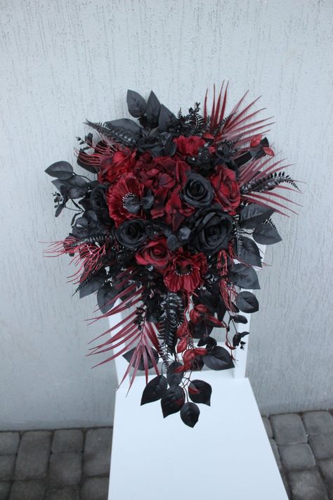 Burgundy black bouquet is a gothic cascading bouquet that embodies a moody and dramatic aesthetic. This silk flower bouquet is a masterpiece of artistry, featuring carefully selected blooms in deep burgundy and black tones, creating a striking contrast that sets a mysterious and enchanting tone for your special day. The cascading design adds an extra touch of elegance, making it a perfect choice for a bride who appreciates the unconventional. This moody bouquet not only serves as a captivating accessory but also enhances the overall atmosphere of your wedding with its unique blend of colors and textures.  ○ Color: burgundy, black ○ Personalization: I can make changes to your wishes ○ Processing time: 1 - 2 weeks ○ Shipping time: 7 - 14 business days NOTE ○ I ship with REGISTERED mail and y Goth Wedding Bouquet Black Flowers, Dark Wedding Flowers Bouquet, Spooky Wedding Bouquet, Gothic Bridal Bouquet, Gothic Flower Bouquet, Moody Wedding Centerpieces, Goth Wedding Bouquet, Black And Red Bouquet, Gothic Wedding Flowers