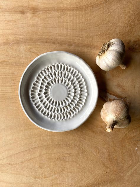 "Love farmhouse style pottery? Then these handmade grater plates are going to make you very happy.  Handbuilt from white stoneware, these plates feature an irregular live-edge rim and are glazed in a classic, creamy white that goes with absolutely everything. The feel is somewhat rustic, but utterly modern. Use them to grate garlic, ginger, or even chocolate. Use them on your table to serve from. An instructional card is included with each plate.  These grater plates are carved freehand to creat Hand Building Pottery Tutorials, Pottery Grater Plate, Garlic Plate Pottery, White Clay Pottery, Household Pottery Ideas, Garlic Dish Pottery, Hand Building Plates, Ceramic Pottery Gifts, Pottery Ideas Small