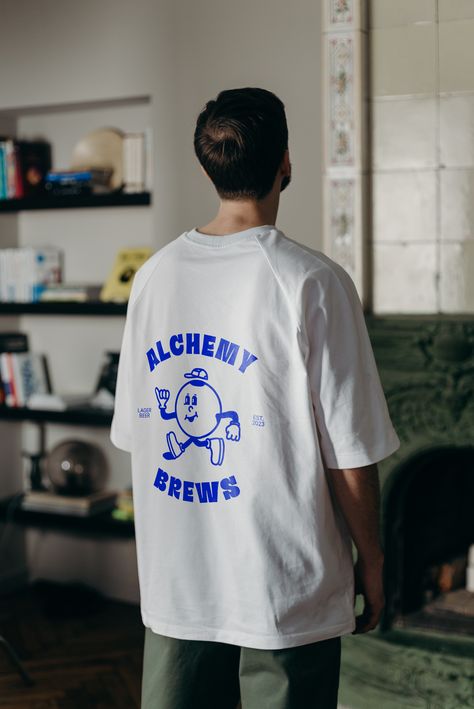 You can see a male or female with short hair wearing a white oversized t-shirt. On the back of the white t-shirt you can see a funky blue print. The print is the logo for alchemy brews, a beer brewery. The logo is a young and hip logo with an illustrated mascot. Do You Think About Me, Bar Tshirt Ideas, Brewery Tshirt, Bar Merch, Brewery Merch, Brewery Logo Design, Beer Logo Design, Craft Beer Design, Brewery Logo