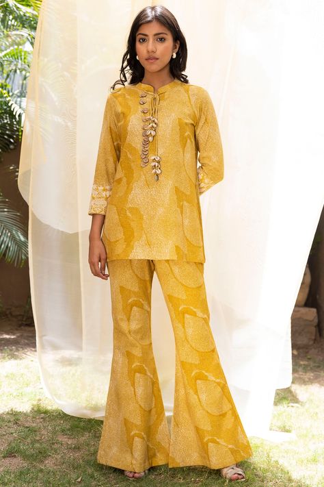 Featuring a mustard shirt top in cotton linen base with shell tassels, wooden buttons, and print including dori and aari embroidery. It is paired with matching pants.  FIT: Fitted at bust and waist. COMPOSITION: Cotton linen. CARE: Dry clean only. Color Shirt Outfit, Co Ords Outfits Indian, Shell Tassels, Tunic With Pants, Suits For Women Indian, Mustard Shirt, Long Blouse Designs, Co Ords Outfits, Pant Suits For Women