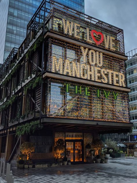 Modern building at twilight with illuminated text We Love You Manchester and The Ivy Manchester City Centre Aesthetic, Manchester Instagram Story, Manchester In Winter, Living In Manchester, Manchester England Aesthetic, Manchester Countryside, Manchester Apartment Aesthetic, Manchester Uk Aesthetic, University Of Manchester Aesthetic