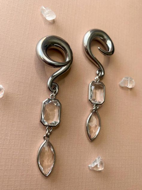 Silver Glass Jewel Dangles Hooks Lightweight Drop Dangle Earrings Gauges/Earplugs Plugs.Regarding sizing: Please be aware my hooks do run slightly smaller- much how single flares are a few decimal points smaller that double flares. Below are the sizes available along with the measurement of the hook at its largest part.6g - 3.7mm2g - 5.7mm0g - 7.7mm00g - 9.6mmThe details:-316 stainless steel spiral hook featuring silver tone plated glass charms.-All earrings are assembled by hand and sold in pai Earrings Gauges, Ear Gauges Plugs, Dangle Plugs, Ear Hangers, Plug Earrings, Glass Charms, Gauged Earrings, Ear Gauges, Plugs Earrings