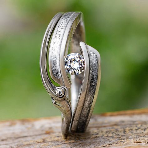 This meteorite bridal set pairs two amazing titanium rings. Both rings are shaped to fit against one another while on your finger. The engagement ring has a meteorite inlay and tension setting, while the wedding band has a tiny bezel set accent stone. A stellar bridal set if you're looking for something non-traditional. *Due to the unique twist design of these rings, they cannot be engraved. Ring 1: Tension Set Engagement Ring with Meteorite (SKU: 4319)Ring width: 10 mm tapered to 3 mmRing Sleev Meteorite Engagement Ring, Tension Set Engagement Rings, Meteorite Rings, Nontraditional Engagement Rings, Wood Engagement Ring, Meteorite Wedding Band, Gibeon Meteorite, Meteorite Jewelry, Space Jewelry