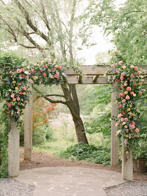 Two "swags" of dusty blues, lavendars, peach, pinks, ivory, creams, and soft yellows are designed on this hand made pergola with growing, wild, wisteria! Pergola Floral Decor, Pergola For Wedding Ceremony, Flowers On Pergola Wedding, Wedding Pergola Flowers, Floral Pergola, Pergola Wedding Decorations, Pergola Flowers, Arbour Wedding, Wisteria Arbor