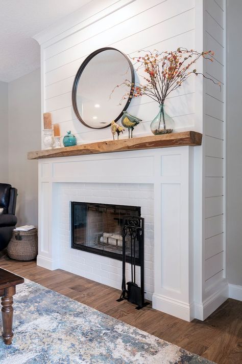 A white shiplap fireplace with warm wood accents. Styled with a round metal mirror, candles, and faux fall stems. Shiplap Fireplace Wall With Wood Mantle, Beach Cottage Fireplace, Coastal Fireplace Ideas Beach, Coastal Fireplace Makeover, Stained Shiplap Fireplace, Tile And Shiplap Fireplace, Shiplap Over Brick Fireplace, Coastal Farmhouse Fireplace, Shiplap And Tile Fireplace