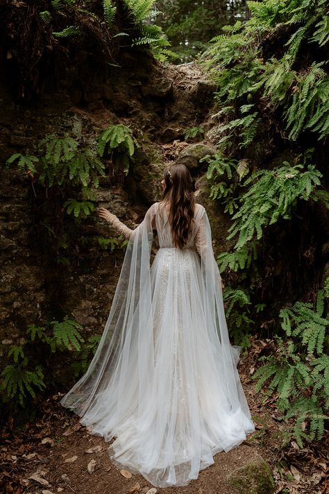 Inspired by ethereal forests of the Pacific Northwest where the trees are draped in mosses. Ivy gown is the ultimate blend of luxury and understated drama. Intriguing and totally unique, Ivy’s vine-like beading travels on your body like branches of a tree. Hand placed beaded appliques float on an illusion mesh bodice, draped with tulle, Ivy is an intricate masterpiece. A fitted beaded skirt is delicately layered with flowy tulle to let in a hint of sparkle throughout the dress, creating a multi Enchanted Forest Wedding Gown, Wedding Dress Mystical, Lord Of The Ring Wedding Dress, Wedding Dress Whimsical Romantic, Forest Inspired Wedding Dress, Moss Green Wedding Dress, Wedding Dresses Nature Inspired, Forest Witch Wedding Dress, Viking Wedding Ideas Dresses