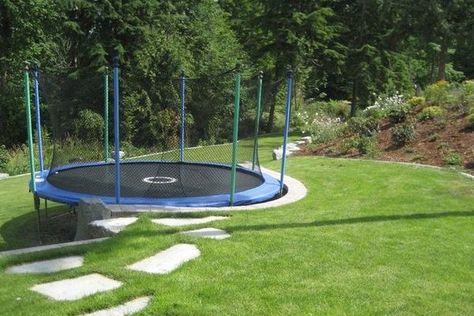 Fortunately, there are still ways you can safely do this, so let's take a quick look at how to set up a trampoline on a slope. Trampoline Uneven Ground, Trampoline Play Area, Sunken Backyard Patio, How To Make A Trampoline Look Nice, Gravel Under Trampoline, Trampoline On Sloped Yard, Sloped Backyard Landscaping On A Budget, Sloping Garden Ideas On A Budget, Landscaping Around Trampoline