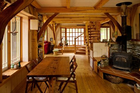 Looking through the dining room towards the spiral staircase and large window. Seats near the wood stove are especially inviting. Timberframe Interiors, Timber Frame Tiny House, Timber Frame Home Interiors, Timber Frame Cabin Plans, Tiny Timber Frame, Timber Frame Interior, Window Layout, Timber Frame Cottage, Cabin Porches