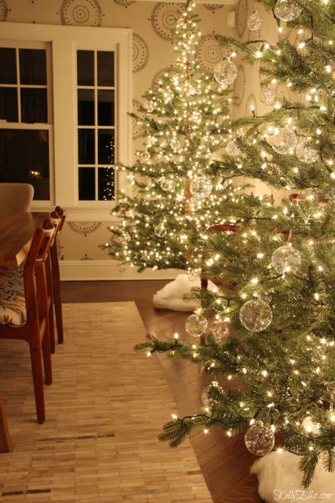 Glowing Christmas Tour at Night - love the pair of glowing sparse trees with clear glass ornaments kellyelko.com #christmasdecor #christmastrees #sparsechristmastrees #christmaslights #christmasdiningroom #christmasornaments #clearornaments #diychristmas #christmascrafts #kellyelko #farmhousechristmas #fixerupperstyle Christ Christmas, Bubble Christmas, Clear Christmas Ornaments, Clear Glass Ornaments, Christmas Apartment, Clear Ornaments, Holiday Arrangement, Minimal Christmas, Christmas Decorating Ideas