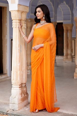 Orange chiffon saree with mukaish dana placement embroidery. Comes with unstitched blouse piece. Components: 2 Pattern: Embroidery Type Of Work: Mukaish dana Fabric: Chiffon Color: Orange Other Details:  Length: Saree: 5.5 mtrs Blouse: 90 cm Approx. product weight: 200 gms Note: The stitched blouse worn by the model is not for sale Disclaimer: Since these products are handcrafted and hand dyed, hence may have slight irregularities and dissimilarities each time it is crafted. This is a natural outcome of human involvement in the process. Occasion: Mehendi and Haldi - Aza Fashions Archana Jaju, Sheer Saree, Rajasthani Bride, Sequins Saree, Fashionable Saree, Blouse Satin, Saree Georgette, Forest Pattern, Purple Saree