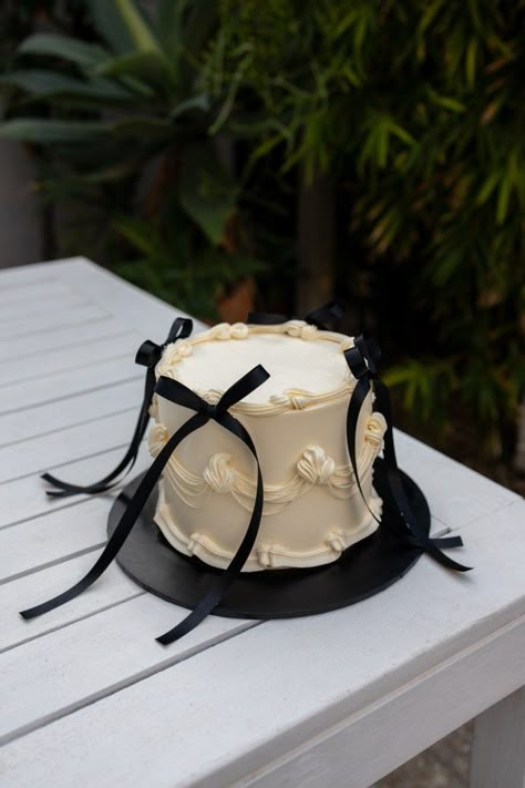 Retro cream piped cake with chic black bows. Cream And Black Birthday Theme, Vintage Cake With Bows, Wedding Cake Retro, Bachelorette Cake Ideas Classy, Small Engagement Cake, Small Vintage Cake, Small Black Cake, Black Theme Cake, Black Tie Cake