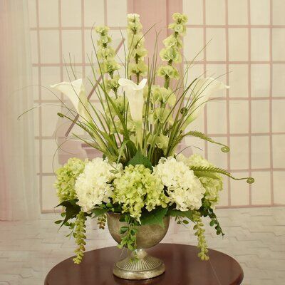 A stunning faux silk mix of white calla lilies, green and white hydrangeas and spectacular bells of Ireland. Arranged perfectly in aaged look silver pedestal vase. Accented with succulents. | Floral Home Decor Calla Lily & Hydrangea Silk Floral Design In Silver Urn Faux Silk in Green / White / Yellow, Size 25.0 H x 18.0 W x 13.0 D in Silk Greenery Arrangements Artificial Plants, Trumpet Vase Arrangement, Floral Arrangements With Hydrangeas, Bells Of Ireland Arrangement, Large Flower Arrangements For Home, Artificial Flower Arrangements For Table, Large Flower Arrangements For Church, Gladiolus Flower Arrangements, Silk Flower Arrangements For Home