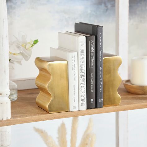 "Find the The Novogratz Contemporary Gold Aluminum Bookends Set at Michaels. com. Creating a boutique experience for the modern family Embrace artistic expression with a style that highlights bold designs with sleek lines, neutral elements, and a minimalist aesthetic. Each wave sided bookend is made of aluminum. Wavy sided bookends have a gold metallic polished finish. One side is flat to rest against the book, while the other is wavy to add a contemporary stile to your shelves. A small piece of Gold Accent Pieces, Gold Bookends, Gold Living Room Decor, The Modern Family, Decorative Bookends, Pinterest Contest, Modern Books, Gold Book, Room Deco