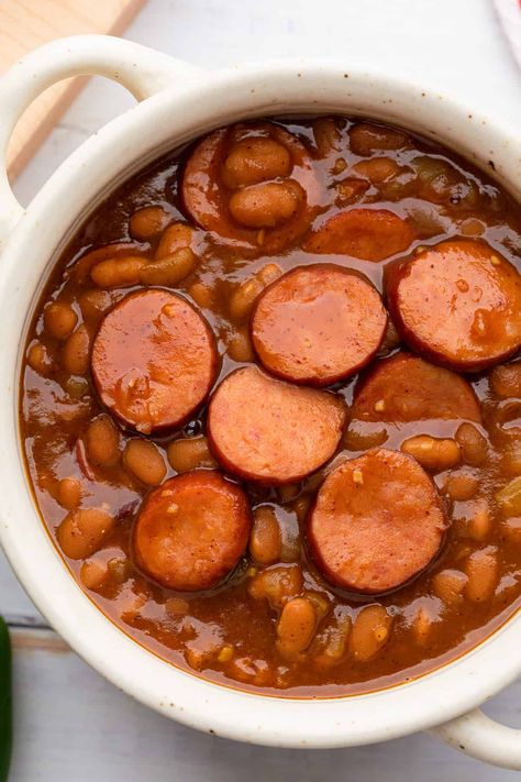 These Texas style baked bean are an excellent side dish that can also serve as a great dinner too. This recipe is easy because it doesn't rely on dried beans, and you don't even need the your oven--they cook up in a skillet or dutch oven right on your stove top. Smoked sausage, chili powder, and jalapeño adds tons of flavor and a piece of corn bread rounds out the dish in true Texas, or Southern style. Round Sausage Recipes, Smoked Sausage Cowboy Beans, Texas Baked Beans Recipe, Beans And Weenies Recipes, Authentic Enchilada Sauce, Bologna Recipes, Sausage Chili, Chile Colorado, Chili Beans