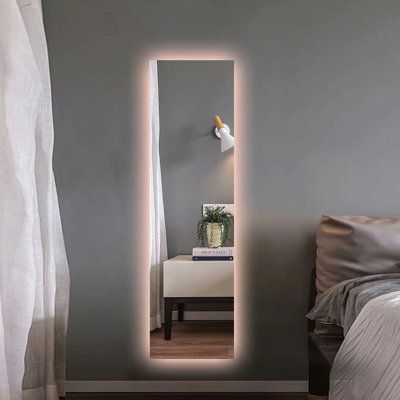 The copper-free mirror is fitted with an integrated LED strip light and add a touch of contemporary style to any bathroom setting. Display it either vertically or horizontally to suit your needs. Elevate your modern bathroom with the frameless mirror, it'll have both you and your home looking better. Light up your day with our LED wall mount bathroom make up mirror today! | Wrought Studio™ LED Backlit Rectangle Wall Mirror w / Smart App Control | Wayfair | Home Decor Mirror Panels On Wall, Lit Makeup Mirror, Long Mirror With Led Lights, Mirror Wall Decor For Bedroom, Mirror Led Lights Bedroom, Mirror With Lights Behind It, Light Up Mirrors, Wall Mirror Ideas Bedroom, Bedroom Reference