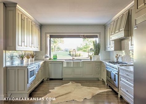 The Howse House Reveal | The U-shaped kitchen features classic white subway tile complemented by pale gray cabinetry. A large picture window overlooks the home’s outdoor living area as well as the tee for hole number one on the golf course beyond. | At Home in Arkansas | November 2016 Kitchen Design With Big Windows, Big U Shaped Kitchen, Large Kitchen Picture Window, Large Picture Window Kitchen, Large U Shaped Kitchen, Picture Window Kitchen, Kitchen With Big Windows, Large Kitchen Windows, U Shaped Kitchen Layout