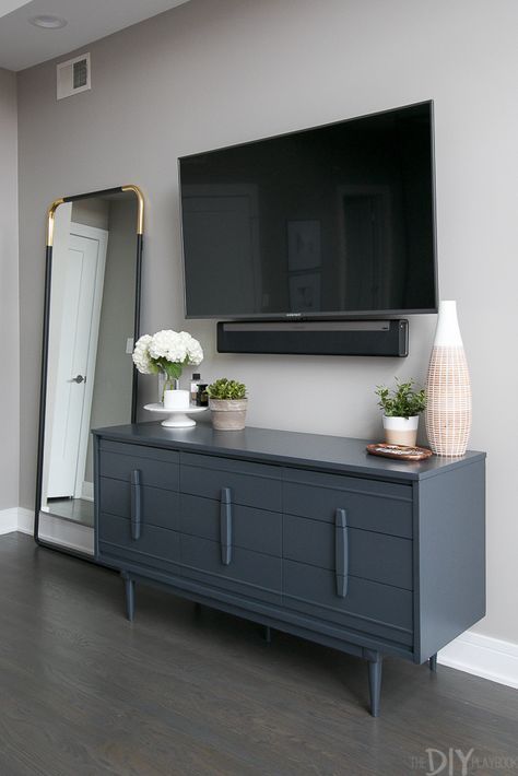 Love this gray bedroom dresser with the TV mounted above it. Plus then you can use the top of it to display pretty accessories. Love the large vase and wood tray from HomeGoods. Don't forget to add some height to the dresser with a cake stand! You can then display perfume and candles on top. (Sponsored Pin). Gray Bedroom Dresser, Bedroom Dresser With Tv, Dresser Under Tv, Dresser Decor Bedroom, Tv Mounted, Dresser With Tv, Tv In Bedroom, Bedroom Dresser, Gray Bedroom