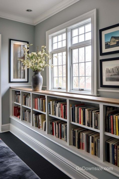 This lovely design enhances the window area with long rows of book storage to serve as a mini library. Bookshelf For Study Room, Below Window Bookshelves, Bookshelf Study Room, Built Ins Around Small Window, Bookcase Around Window Living Room, Window Seat And Bookshelves, Built In Book Shelves Around A Window, Cabinets Under Window Living Room, Under Window Bookcase