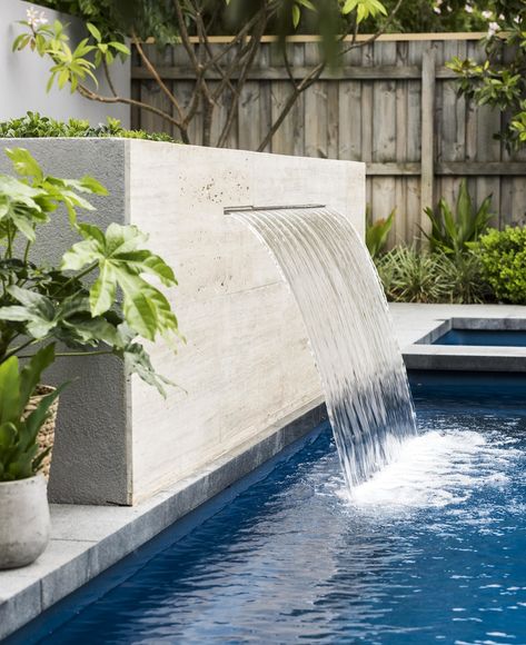 A travertine-clad water feature flows into the fibreglass swimming pool. Swimming Pool Fountains, Swimming Pool Waterfall, Pool Paving, Water Feature Wall, Travertine Pool, Pools Backyard Inground, Ikan Koi, Pool Water Features, Pool Remodel