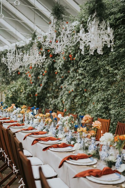 Chandelier decor with orange and blue flowers and tablescape Orange And Blue Wedding Table Decor, Burnt Orange Blue Wedding, Blue And Orange Table Setting, Blue And Orange Wedding Table, Light Blue And Orange Wedding, Orange And Cream Wedding, Orange Wedding Table, Navy And Orange Wedding, Colour Scheme Wedding