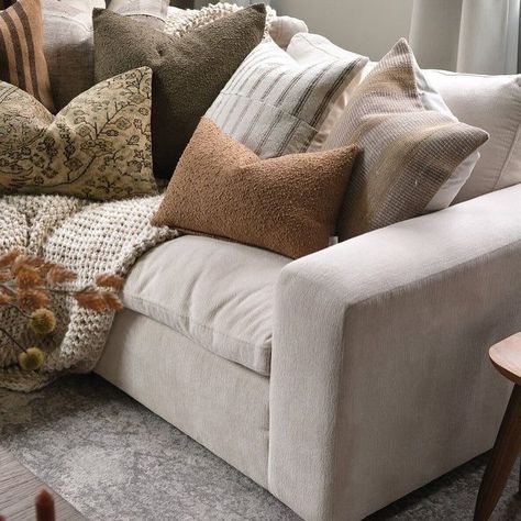 The centerpiece is a plush, neutral-toned sofa adorned with an assortment of textured throw pillows in various earthy hues, including shades of beige, brown, and muted green. The pillows feature a mix of patterns and materials, such as stripes, florals, and solid textures, creating a rich and layered look. #farmhouseliving #cozycorner #homedecor #interiordesign The Pillows, Earthy Hues, Textured Throw Pillows, Muted Green, Beige Sofa, Brown Sofa, Shades Of Beige, Farmhouse Living, Cozy Corner