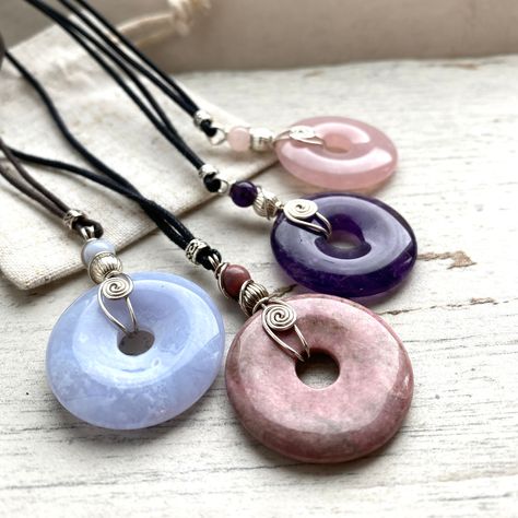 "*AA Quality  gemstones. *Rose Qaurtz and other Purple and pink semi precious stone donut pendants, *I wrapped them in 925 sterling silver wire spiral design. *This will stay beautiful forever. *I guarantee our wire wrap from unraveling.  *Each Natural crystal is attached to a strong dyrable waxed cotton cord. ADJUSTABLE LENGTH Slide the knots between 28\" and 14\". Versatile Jewellery, a women's gemstone chakra pendant, in beautiful pink Rose Quartz. My  unique Silver wrapped spiral bail is str Donut Crystal Necklace, Crystal Donut Necklace, Random Diys, Wire Wrapped Crystal Pendant, Crystal Wrap, Donut Pendant, Chakra Pendant, Pink Rose Quartz, Rock Jewelry