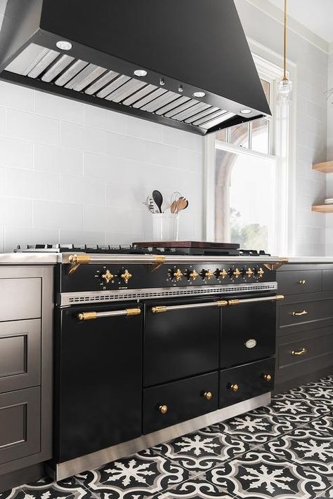 A Lacanche Range sits on a black and white cement floor tiles between black shaker drawers adorned with brass pulls and a white quartz countertop. White Cement Floor, Lacanche Range, Full House Remodel, Cement Floor Tiles, White Cement, Bathroom Redesign, Isamu Noguchi, Quartz Countertop, Cement Floor