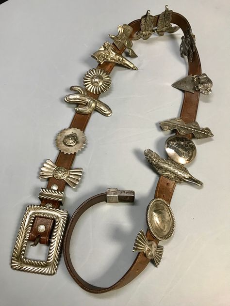 Arnold Goldstein Sterling Silver Concho Brown Belt Weight: 958 Grams, Lbs 2.1 Approximate Measurements: Belt Length: 47" Belt Width: 1" Charms from 2" to 3.5" Arnold Goldstein sterling silver concho brown belt 14 charms. Arnold Goldstein’s passion for Western and American Indian art began in his teens. At the age of 20, he was earning a living as a professional sculptor. Goldstein’s range as an artist, sculptor & designer is impressive. His western sculptures are reminiscent of Remington’s a Vintage Western Jewelry, Indian Inspired Jewelry, Belts Aesthetic, Western Inspiration, Belt Buckle Jewelry, Western Womens Fashion, Western Sculpture, Work Belt, Looks Country