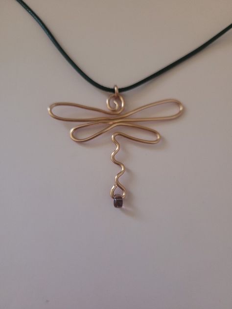 This is an image of an abstract wire dragonfly pendant made of copper wire with a tiny lilac teardrop bead at the bottom of the dragonfly's tail.  It is on a black cord necklace Wire Jewelry Dragonfly, Wire And Bead Dragonfly, Words Made Out Of Objects, Dragonfly Jewelry Diy, Homemade Wire Earrings, Diy Wire Jewelry Necklaces, Dragonfly Earrings Diy, Diy Wire Necklace Pendant, Jewelry Making With Wire