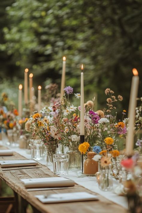 wooden table decorated with wildflowers and tall candles for a wedding reception Whimsical Theme Wedding, Whimsical Garden Wedding Table Decor, Whimsical Wedding Theme Romantic, Whimsical Garden Wedding Theme, Whimsical Wedding Table Decor, Wildflower Wedding Theme Table Settings, Wildflower Table Setting, Wedding Theme Outdoor, Whimsical Reception