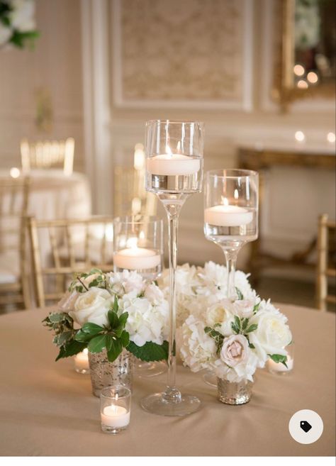 High White Centerpiece, White Floating Candles Wedding, Candles And Flowers Centerpieces Wedding Simple, Stemmed Candle Holders Wedding, Wedding High Top Table Flowers, Guest Book Floral Arrangement, Candles And White Roses Centerpiece, Low Centerpieces Wedding Round Table With Candles, Raised Wedding Centerpieces