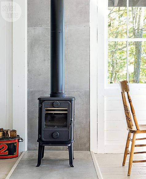 This cozy lake house in Port Carling, Ont., boasts a fresh seaside-chic vibe while paying homage to old-school Muskoka. Tiles Behind Wood Stove, Corner Wood Stove Ideas Modern, Concrete Wood Stove Surround, Small Freestanding Fireplace, Old School Fireplace, Cement Board Behind Wood Stove, Tile Wall Behind Wood Stove, Wood Burning Stove Tile Surround, Wood Stove Surround Metal