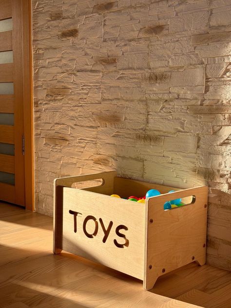 Keep your child's play area tidy and stylish with this beautifully handcrafted wooden toy box. Designed with both functionality and aesthetics in mind, this toy box is the perfect addition to any nursery, playroom, or living space. Features: Premium Quality Wood: Made from durable, high-quality wood that ensures longevity and sturdiness. Modern Design: Features a sleek, natural wood finish with a charming "TOYS" cutout that adds a playful touch. Spacious Storage: Offers ample space to store toys Toybox Ideas, Toy Box Wooden, Toy Storage Furniture, Wood Toy Box, Baby Nursery Storage, Designer Homes, Wooden Toy Boxes, Cnc Ideas, Toy Organizer