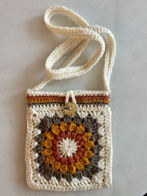 Introducing our charming Small Crochet Bag, meticulously crafted with a delightful sunburst granny square design  in retro 70s colors, giving fun Bohemian flair. This bag will easily fit your phone and your other essentials and has a cute button closure to keep it all safe and secure! Granny Square Crochet Crossbody Bag, Crochet Projects Using Granny Squares, Granny Square Gifts Ideas, Granny Square Accessories, Granny Square Phone Bag, Small Crochet Bag Pattern, Pochette Granny Crochet, Crochet Bag Pattern Free Easy Handbags, Small Granny Square Bag