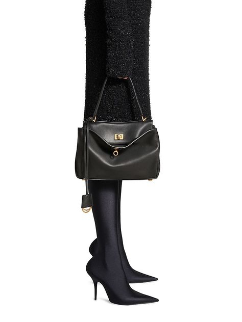 Find BALENCIAGA Rodeo Small Handbag on Editorialist. The Balenciaga Rodeo Small Handbag is crafted from smooth calfskin and features a top handle, a removable shoulder strap, aged-gold hardware, and a turn lock closure. The handbag also has a wide front pocket, one main compartment, one inner zipped pocket, two flat pockets at the back, side snaps, and four brass feet. The interior is lined with nappa lambskin. The handbag measures 11.4 x 7.9 x 3.9 inches and is made in Italy. Balenciaga Women, Flat Pouch, Lock It, Medium Handbags, Balenciaga Black, Large Pouch, Leather Keyring, Balenciaga Bag, Split Rings