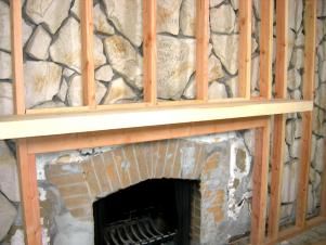 Want to get rid of an old rock wall but it requires too much demo? Cover it up with framing and drywall. Mantel On Rock Fireplace, Covering Up Stone Fireplace, How To Update Rock Fireplace, Covering Rock Fireplace, Rock Wall Fireplace Makeover, Stone Wall Fireplace Makeover, Old Rock Fireplace Makeover, Redoing Fireplace Ideas, Update Stone Fireplace