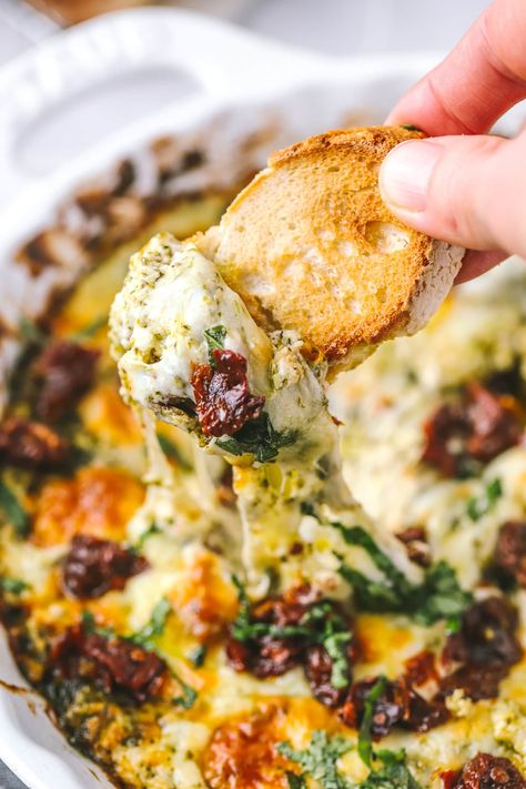 This easy cheesy baked pesto dip is packed with flavour and juicy sun-dried tomatoes. It's an easy appetizer for the holidays and game-day! Easy Dinner Dips, Last Min Appetizers, Goat Cheese Sun Dried Tomato Appetizer, Tuscan Cheese Dip, Dips For Focaccia, Sun Dried Tomato Pinwheels, Pesto Sundried Tomato Cream Cheese Dip, Simple Savory Appetizers, Cream Cheese Pesto Dip