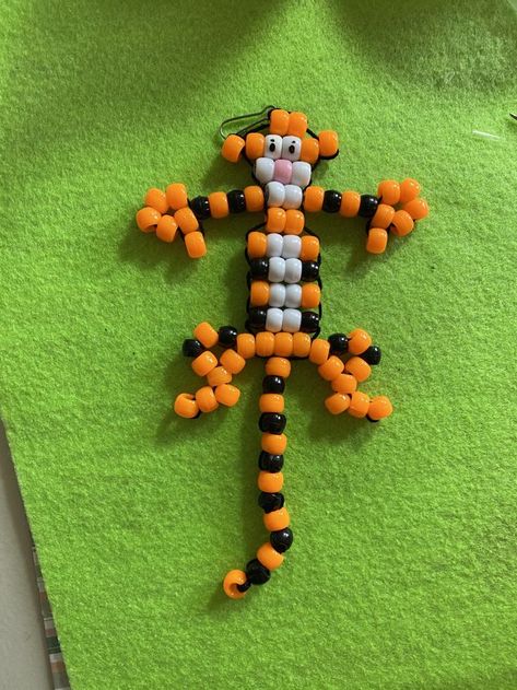 Tiger Bead Pet. Lay out the beads in this pattern. We used drinking straws cut lengthwise to put the beads on each row, then cut the straw to the length needed. Straws will not even show. Lace together Tiger starting with top of head to feet using a tapestry needle. We finished the tail separately and then attahed it. See all Pinterest patterns at: "Bead Pets on Steroids" and https://www.youtube.com/channel/UC5rlDi0oy7YoVMcdNeaTpIw/videos. Tri Bead Crafts, Bead Pets Pattern Diy Tutorial, 90s Bead Animals, Bead Pets Pattern Easy, How To Make Beaded Animal Keychains, Pony Bead Animals Patterns, Bead Pets Pattern, Pony Bead Patterns Easy, Bead Animals Patterns Easy