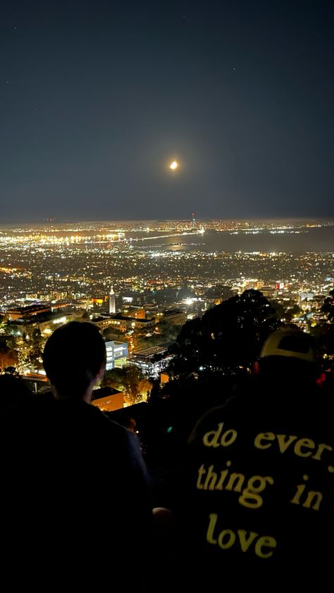 Two people are looking at the beautiful view of San Francisco. It is night so the lights are bright and the sky is clear. The back of the boy’s sweater on the right reads “do everything in love.” Night Hike Aesthetic, Citylights Night Aesthetic, Quiet Photos Night, Bff Travel Goals, Travel Pictures Airport, City Landscape Aesthetic, Night View Aesthetic, Girl Best Friends Aesthetic, Bestie Vacation