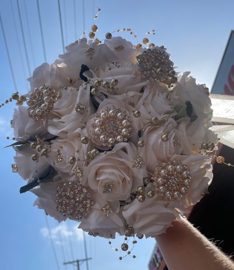 Handmade quinceañera bouquet with Ivory color shade of roses. Finished off with Gold brooches. *Please note brooches can change in style based on availability*   Decor can be changed upon request.  *This is a made to order bouquet* Champagne Ramo Quince, White Quince Bouquet, Brown Quinceanera Theme, Quince Flower Bouquets, Gold Quinceanera Bouquet, Vintage Quinceanera Ideas, White Quinceanera Theme, Beige Quinceanera Dresses, Royalty Quinceanera Theme