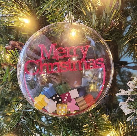 "This custom-made ornament is the perfect gift for the board game collector that has everything. The 4\" x 2\" hard plastic ornament is filled with game pieces and bits. Each ornament contains at a minimum ALL of the following:  5 randomly selected meeples 4 randomly selected wooden cubes 3 randomly selected 12mm dice 1 3D printed \"Merry Christmas\" (color may vary) *All boardgame bits are randomly selected. Colors and cards will be random. These are pictures are of the original ornaments made for this listing.  *SarDesignLab is not affiliated with any board game companies or distributors." Handcrafted Ornaments, Wooden Cubes, Christmas Color, Christmas Custom, Game Pieces, Custom Christmas, How To Make Ornaments, Game Item, Christmas Colors