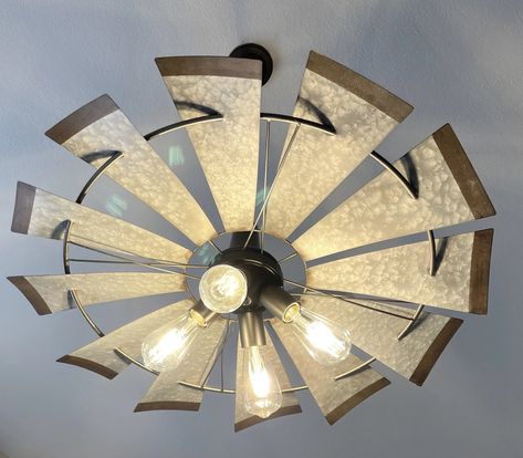 Bold, Unique, Current & Dramatic! Our original, heavy galvanized windmill chandelier light fixture for your modern or rustic farmhouse lighting. Hang this over your table or even in your bedroom for a unique farmhouse chandelier. Featured in Country Sampler magazine. Product Details 30" wide and 9.5" tall Heavy Metal Galvanized Windmill (Non-motorized) (4) 60W equivalent LED or CFL Bulbs or 60W Incandescent (not included) Shown with Edison Filament bulbs (not included but available) Bronze Chain Country Kitchen Ideas Farmhouse Style, Rustic Outdoor Lighting, Nautical Light Fixtures, Windmill Ceiling Fan, Vintage Windmills, Metal Windmill, Unique Ceiling Fans, Windmill Decor, Modern Farmhouse Lighting