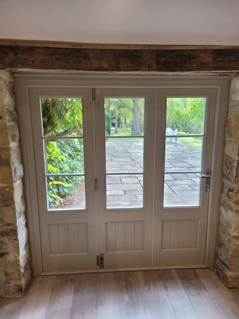 White bi-fold doors in a conservatory. The door is closed with a view out onto a large garden. Bifold Doors With Windows, Green Bifold Doors, Bifold Doors Kitchen, Bifold Doors Extension, Bifold Garage Doors, Oak Bifold Doors, White Bifold Doors, 1960’s Kitchen, Internal Bifold Doors