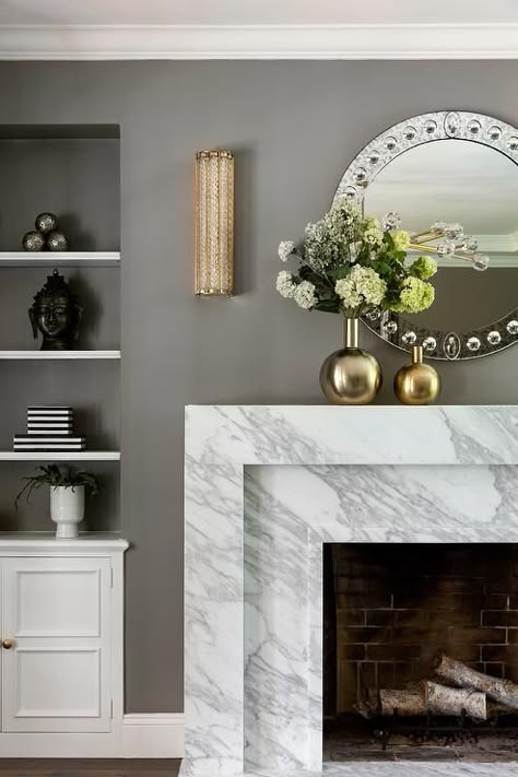 White shelves are fixed in a gray alcove or white built-in cabinets and beside a marble art-deco style fireplace topped with gold vases. Mirror Over Fireplace, Art Deco Fireplace, Style Fireplace, Marble Fireplace, White Fireplace, Fireplace Mirror, Cottage Living Rooms, Transitional Living, White Shelves