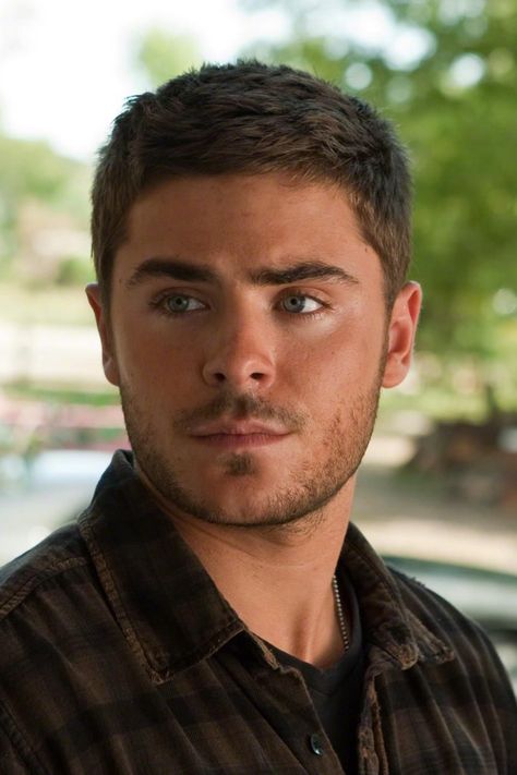 Zac Efron's character, Logan Thibault, in "The Lucky One" had a fashionable and textured haircut. Zac Efron Short Hair, Zac Efron Haircut, Iconic Haircuts, Buzzcut Men, Zac Efron Hair, Trendy Layered Hairstyles, Vintage Haircuts, Zach Efron, Dark Hair Blue Eyes