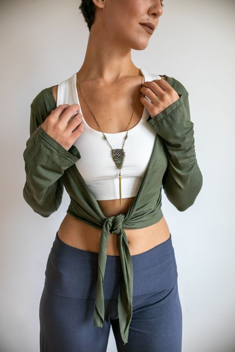 This cute yoga wrap ballet mini jacket with sleeves is versatile and fun to wear. It ties in the front or can be wrapped around and tied in the back. Dress up any sleeveless outfit. Slims the arms and adds a layer of warmth or sun protection. Great under vests!  Made from a deliciously soft fabric with wonderful stretch and feel.  Shown here in Olive over the Shanti yoga Bra in White. Worn with Sage Palazzo Pants in Gray. Machine wash delicate or hand wash. Hang to dry. Ballet Jacket, Yoga Wrap Top, Wardrobe Plan, Mini Jacket, Ballet Clothes, Sleeveless Outfit, Wardrobe Planning, Goddess Dress, Cap And Gown