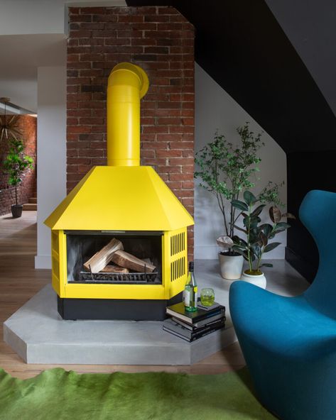 A yellow fireplace sits in a living room with a bright teal chair in the corner and decorations all around. Victorian Aesthetics, Post Modern, Postmodernism, Small Living, Creative Director, New Life, Pittsburgh, York City, New York City